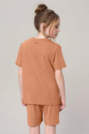 Girl in mocha brown basic tee and shorts set, shown from the back, neutral background