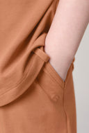 Close-up of hand in pocket of mocha brown girls basic tee, soft athletic fabric.