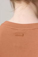 Close-up of mocha brown tee shirt back with stitched neck detail and fabric logo patch