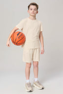 Boy in sand-colored basic tee and shorts, holding basketball, athletic casual outfit