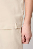 Close-up of a boy wearing a sand-colored basic tee and shorts, showcasing soft fabric texture.