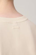 Close-up of a beige boys' basic tee shirt collar with subtle back label detail.