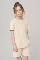 Girl wearing sand-colored basic t-shirt and shorts set, neutral background, athleisure style