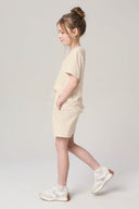 Girl in sand beige basic tee and shorts set, side view, casual athleisure outfit