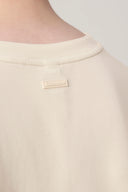 Close-up of beige crew neck t-shirt back with small tonal Seissense label