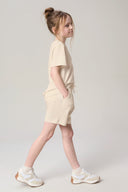 Girl in sand beige basic tee and matching shorts, casual athleisure outfit, studio setting