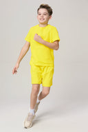Boy smiling in bright yellow t-shirt and shorts set, casual summer activewear
