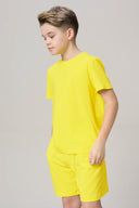 Boy in yellow short-sleeve athletic tee and matching shorts against neutral background