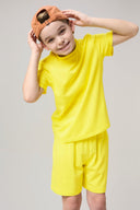 Smiling boy in yellow athletic t-shirt and shorts, wearing a tan cap on a neutral background