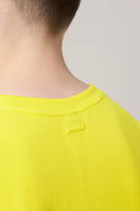 Close-up of a boy wearing a yellow basic tee with a small tag at the back neckline