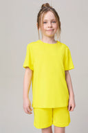 Girl wearing yellow short-sleeve activewear tee and shorts, neutral background