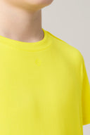 Close-up of youth wearing bright yellow short sleeve crewneck tee, minimal design