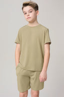 Boy wearing light olive green short sleeve tee and matching shorts, neutral background