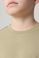 Close-up of boy wearing light olive green crewneck athletic tee with small chest logo
