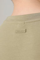 Close-up of light olive green t-shirt neck and label detail, soft cotton fabric