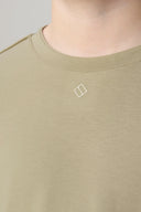 Close-up of sage green crew neck tee with small chest logo, soft athleisure fabric
