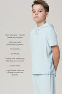 Boy in light blue athletic tee and shorts, short sleeves, side logo trim, neutral background.