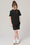 Girl wearing charcoal hooded tee and matching shorts with white sneakers, standing in studio