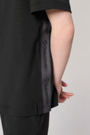 Side view of a charcoal girls' hooded tee with logo taping on the hem and sleeve.