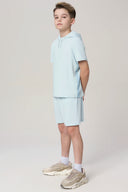 Boy wearing light blue short-sleeve hooded activewear set and sneakers