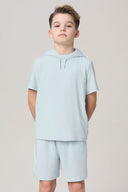 Boy in light blue short-sleeve hooded tee and shorts, athleisure outfit, studio background
