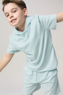 Boy wearing light blue hooded tee and matching athletic shorts, neutral background