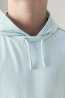 Close-up of a light blue boys' hooded athletic tee with drawstrings and subtle logo.