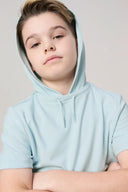 Boy wearing light blue hooded t-shirt, short sleeves, neutral background, activewear