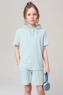 Girl wearing glacier blue hooded tee and shorts, holding blue headphones