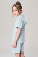 Girl wearing light blue hooded short-sleeve tee and matching shorts, side view