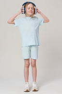 Girl in light blue hooded tee and shorts set, wearing headphones, standing in studio