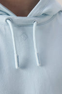 Close-up of light blue hooded tee with drawstrings and subtle logo detail.