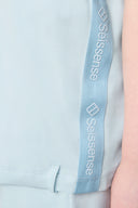 Light blue girls’ activewear hoodie with side logo detail and soft fabric close-up