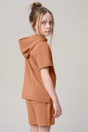 Girl wearing mocha brown hooded tee and shorts, neutral background, athleisure fashion