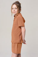 Girl wearing mocha brown hooded tee and matching shorts, side view, athleisure set