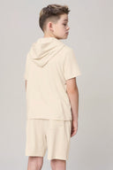 Boy wearing sand-colored hooded tee and shorts, back view against plain background