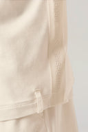 Close-up of sand-colored boys' hooded tee with embossed logo trim and soft fabric texture