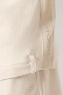 Close-up of sand-colored girls' hooded tee with subtle logo details and soft fabric texture.