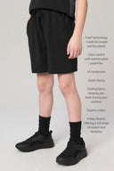 Boy wearing charcoal athletic shorts with pockets, drawstring waist, and black sneakers standing indoors.