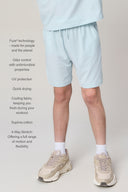 Boy wearing light blue relaxed athletic shorts, neutral sneakers, and white socks