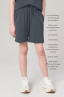 Girl wearing relaxed granite athletic shorts with drawstring, side pockets, and white sneakers.