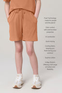 Girl wearing mocha brown relaxed shorts, drawstring waist, white sneakers, neutral background