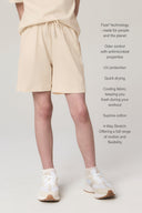Girl wearing relaxed sand shorts with elastic waist, paired with white sneakers, against a neutral background.
