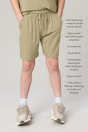 Boy wearing relaxed fit willow green shorts with drawstring waist and sneakers, front view