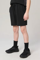 Boy wearing charcoal athletic shorts with drawstring, black socks, and black sneakers