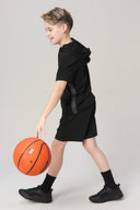Boy in black athletic shorts and hoodie playing basketball indoors