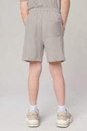 Back view of boy wearing driftwood-colored shorts with elastic waist and sneakers