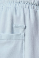 Close-up of light blue athletic shorts with elastic waistband, front pocket, and raised logo patch