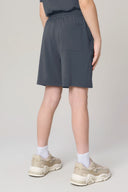 Boy wearing granite gray athletic shorts with pocket, white socks, and beige sneakers