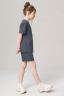 Girl in granite gray activewear shorts and t-shirt set with white sneakers